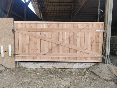Porta d'un corral de fusta amb tirador d'acer
