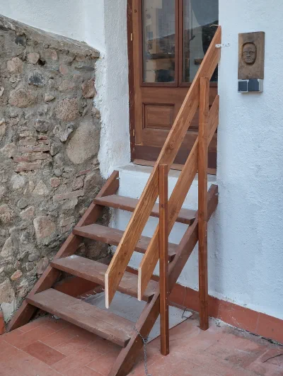 Escala i barana de fusta per poder accedir al replà de la porta